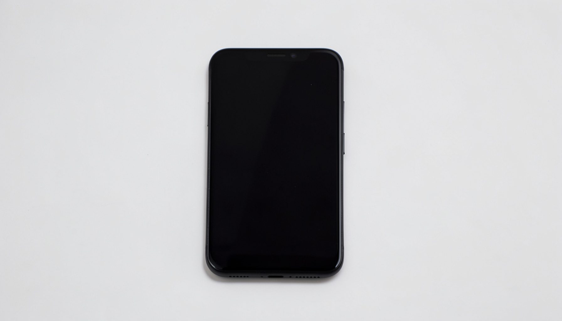 Budget smartphone with a glossy black front panel, simple design, on a light neutral background